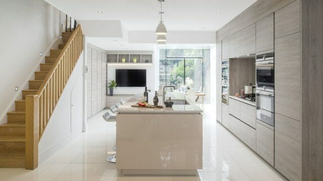 Open-plan kitchen living space with handleless cabinetry, gloss island and integrated appliances in a terraced house extension, Ashley Jay Kitchens Horsham