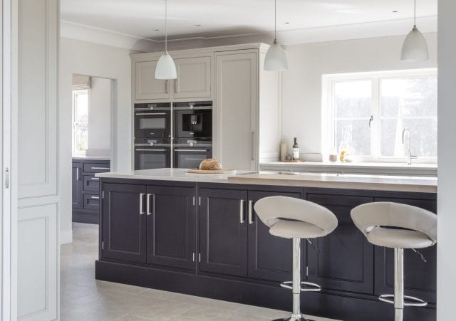 Classic Ashley Jay kitchen with dark island, painted cabinetry, pendant lights and breakfast bar seating