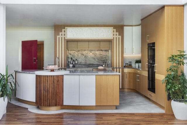 Ashley Jay kitchen with curved island, wood cabinetry, integrated ovens and decorative splashback
