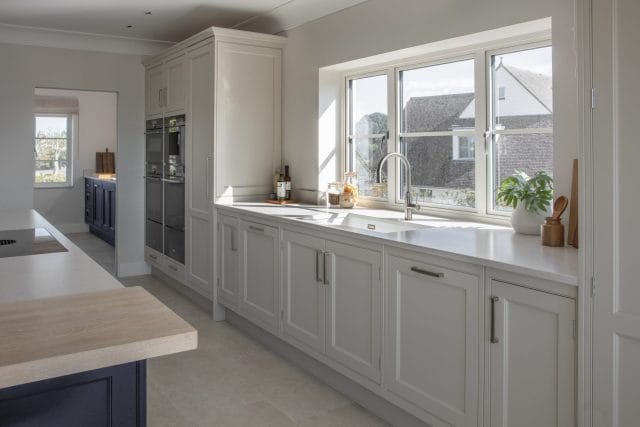 Light grey Ashley Jay kitchen with shaker-style cabinetry, large windows and bright worktops
