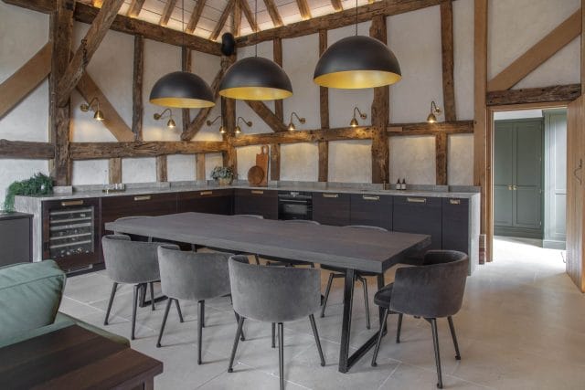 Bespoke dark kitchen in a converted barn with exposed timber beams, concrete worktops and large pendant lights, Ashley Jay Kitchens