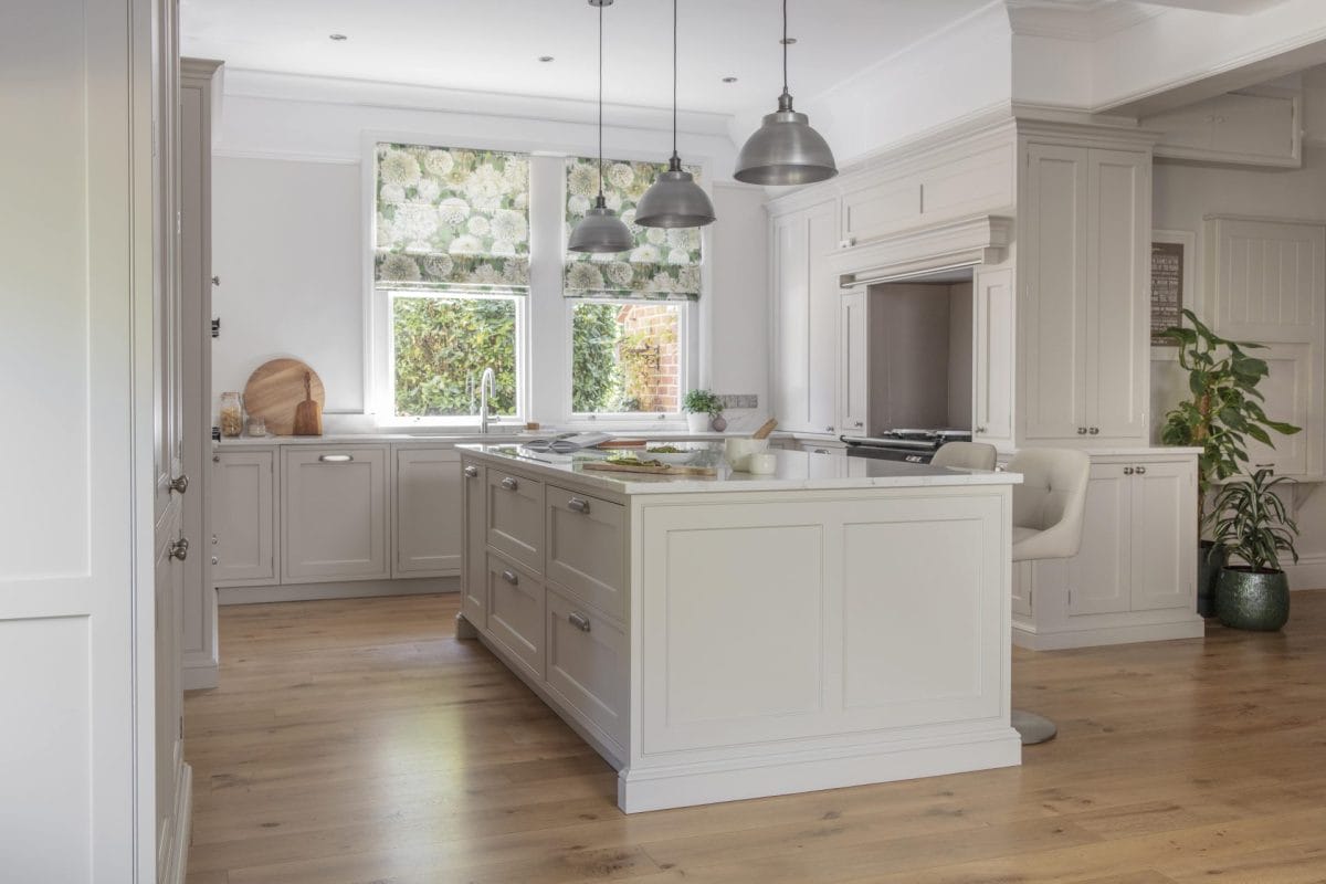 Bright, timeless shaker kitchen with a large central island, painted cabinetry, pendant lighting and floral Roman blinds creating a soft, elegant feel.