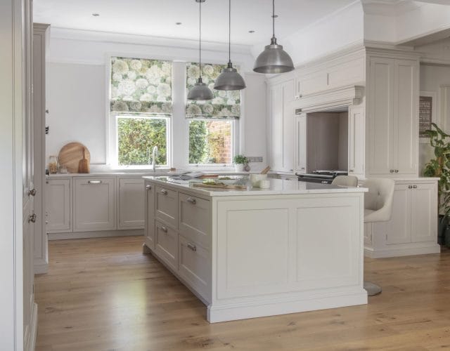 Bright, timeless shaker kitchen with a large central island, painted cabinetry, pendant lighting and floral Roman blinds creating a soft, elegant feel.